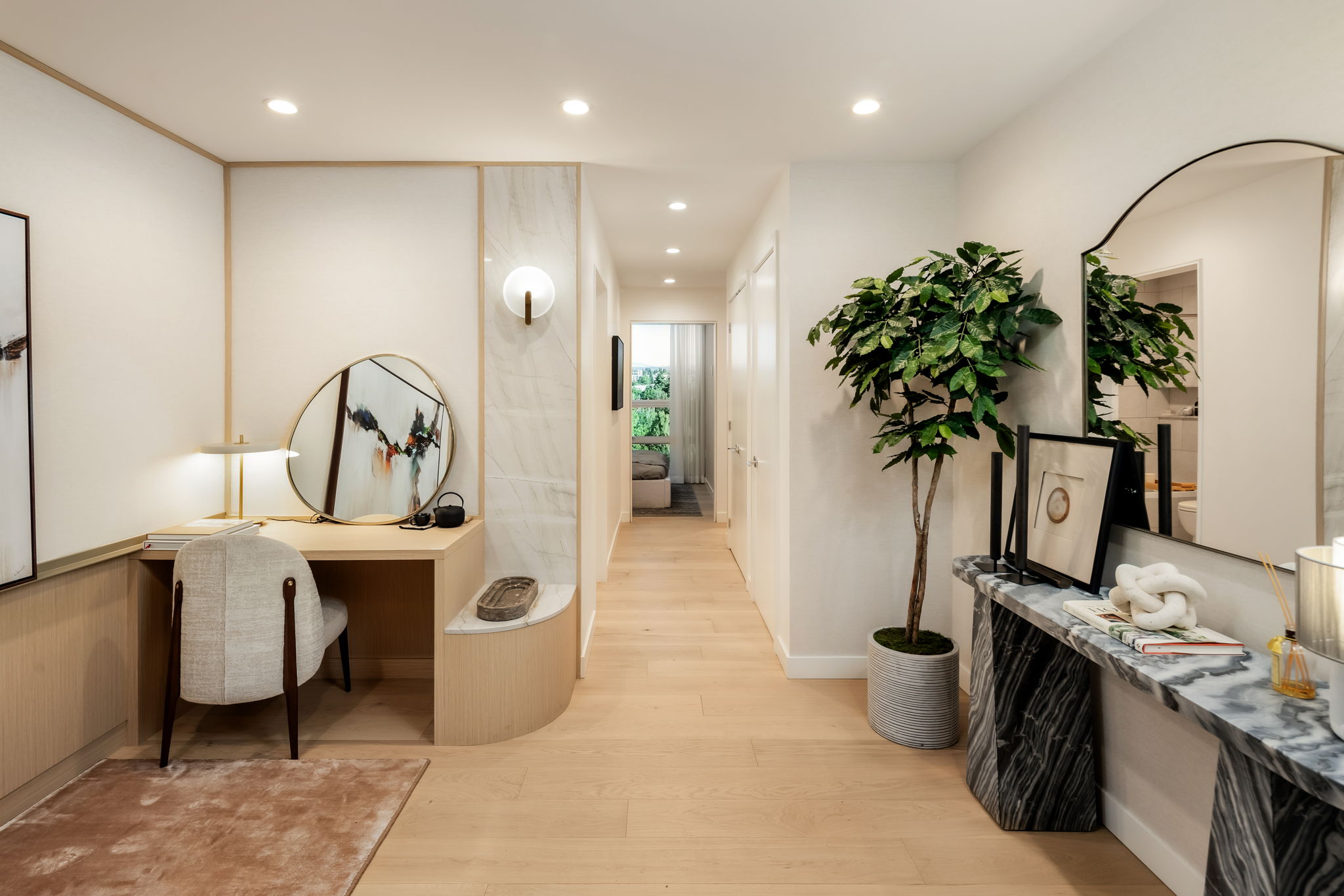 Modern condo at Ashleigh Oakridge foyer with built-in desk, integrated storage, marble accents, and warm wood flooring leading to bedroom