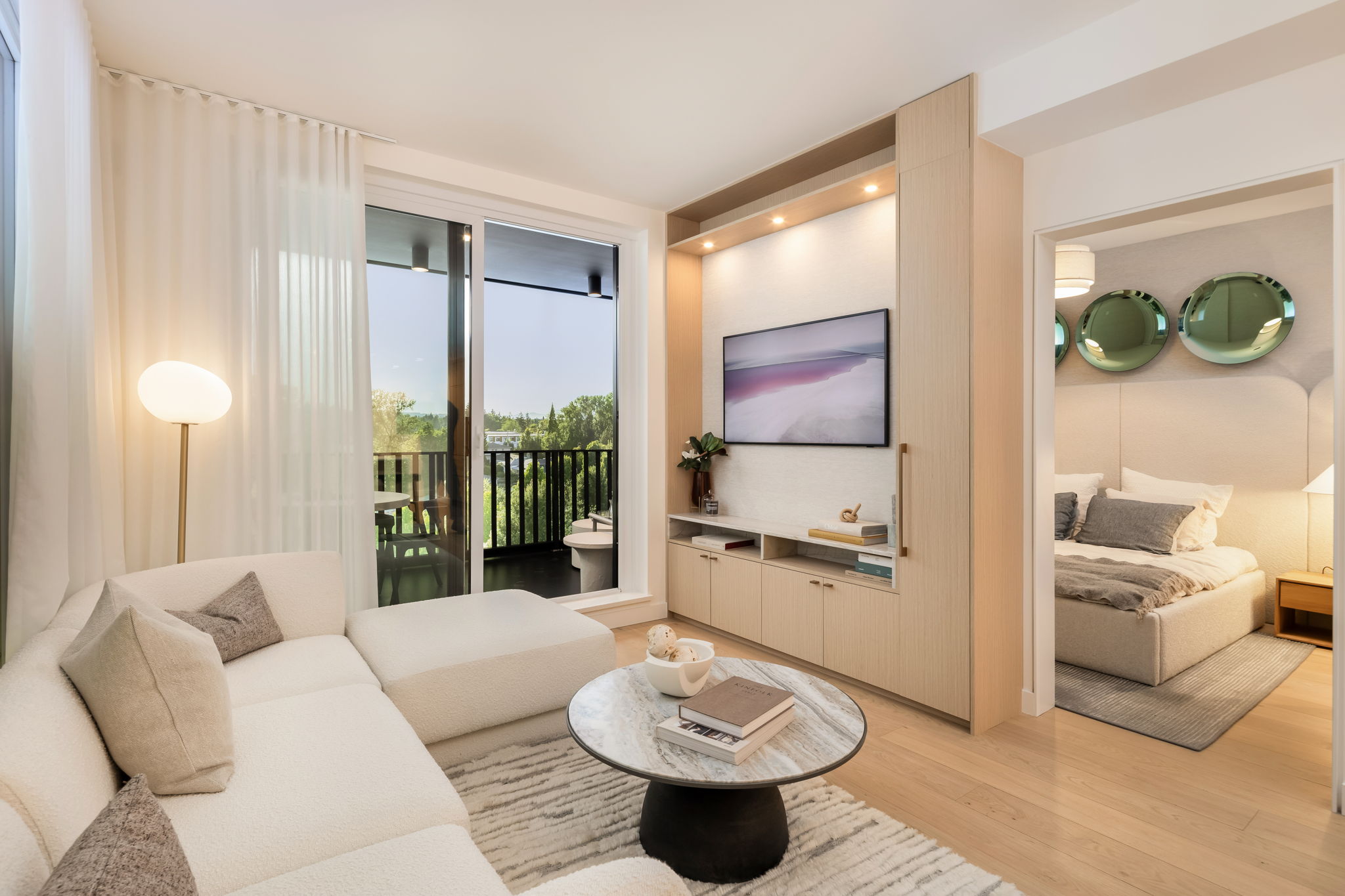 Bright and modern condo living room with custom millwork, floor-to-ceiling windows, private balcony access, and a cozy bedroom retreat in a contemporary concrete home.